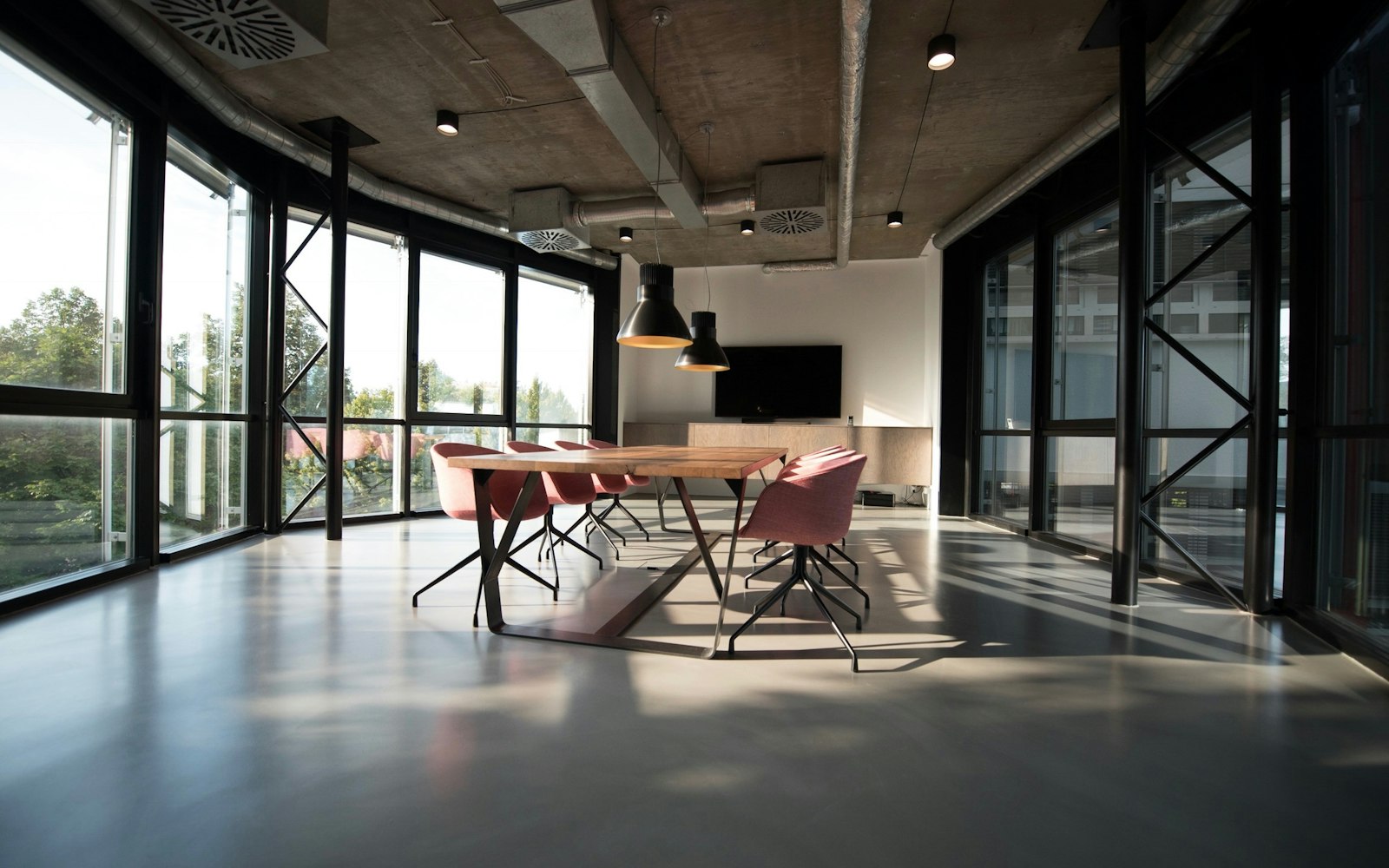 A sunlit coworking room with tables and large windows