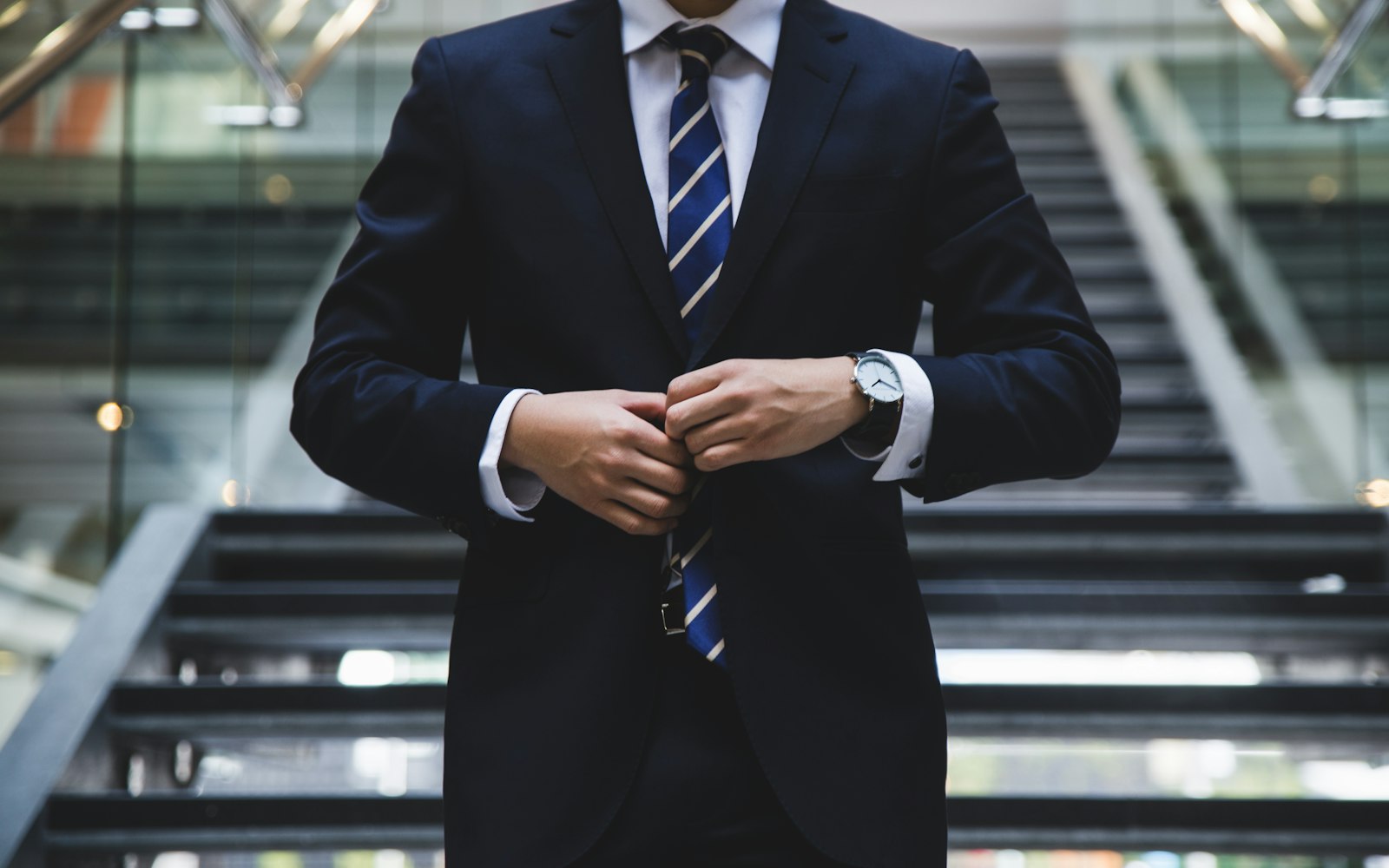 A business professional adjusting a jacket in a corporate space