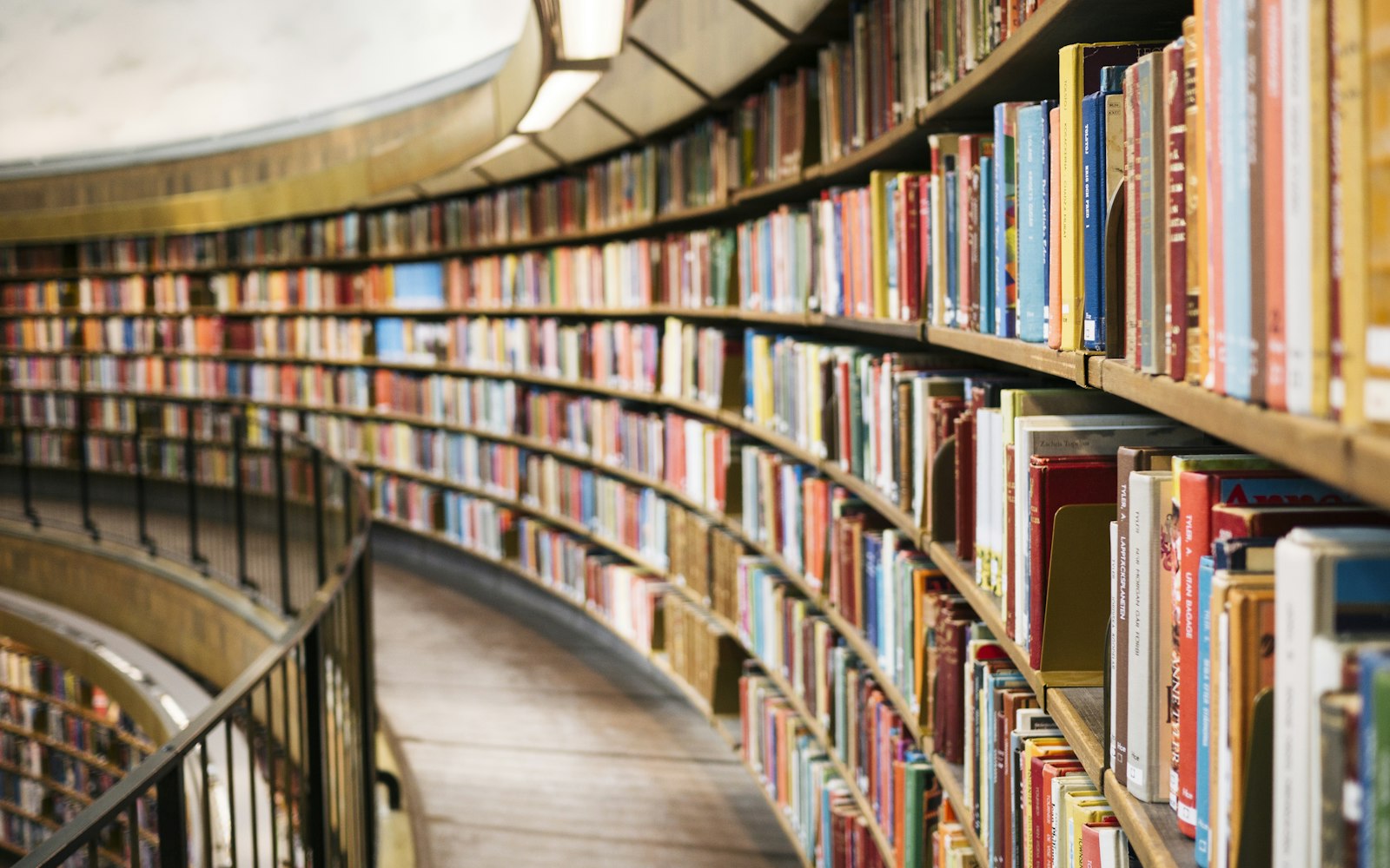 A large library reading room with arched shelves of books