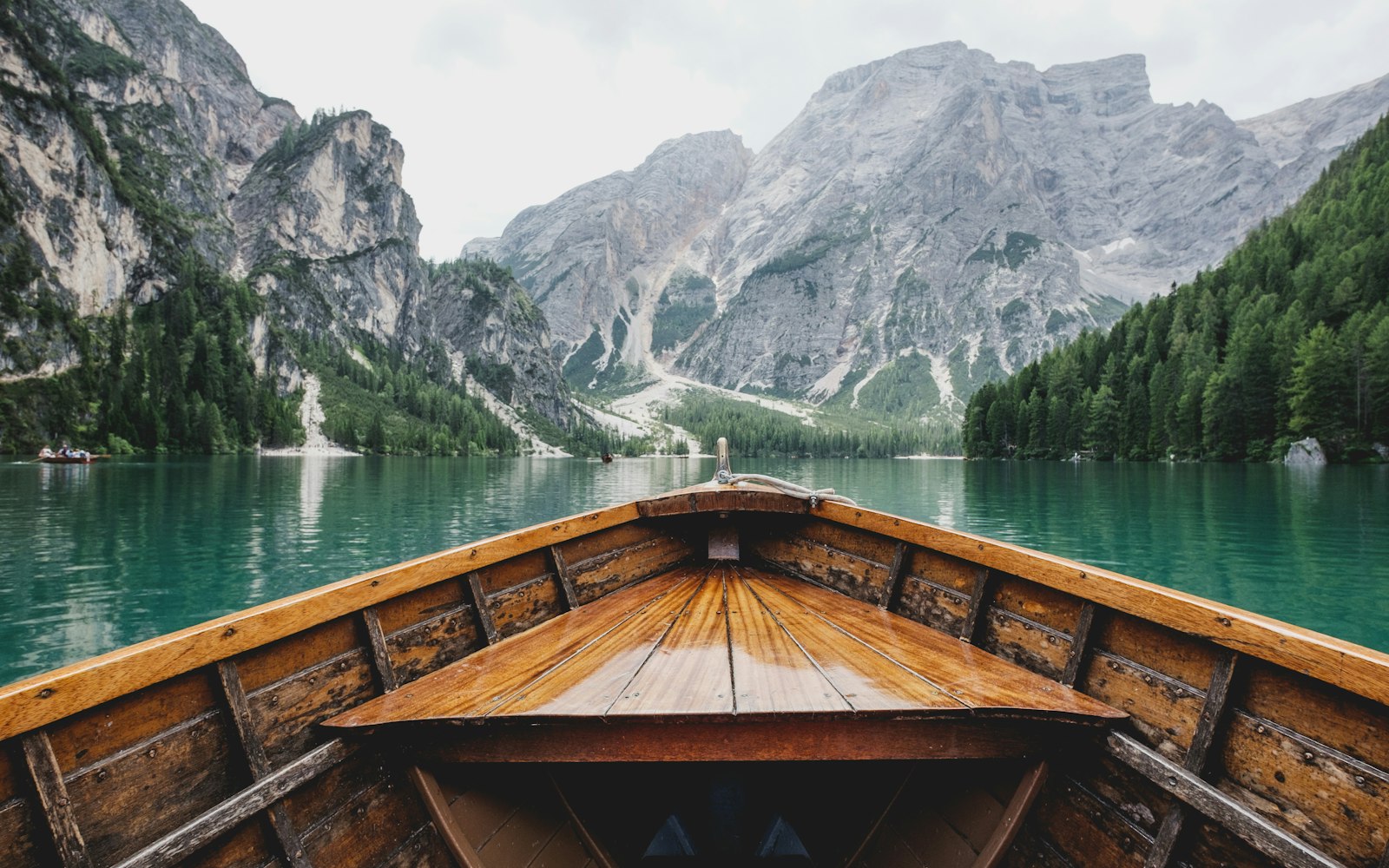 A wooden boat on a calm lake surrounded by mountains