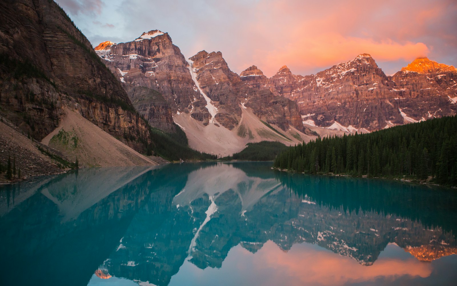A turquoise mountain lake beneath a pink evening sky